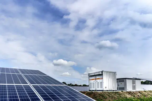Battery storage containers beside a ground-mounted solar array