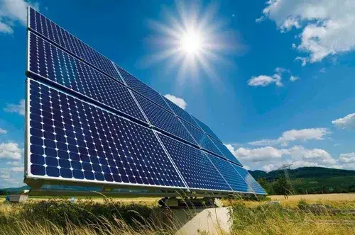 Ground-mounted solar panel array angled toward a bright sky