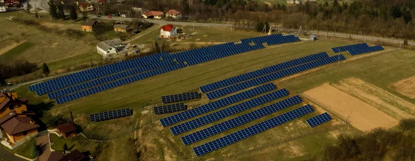 Aerial view of a large solar panel array beside dense green forest